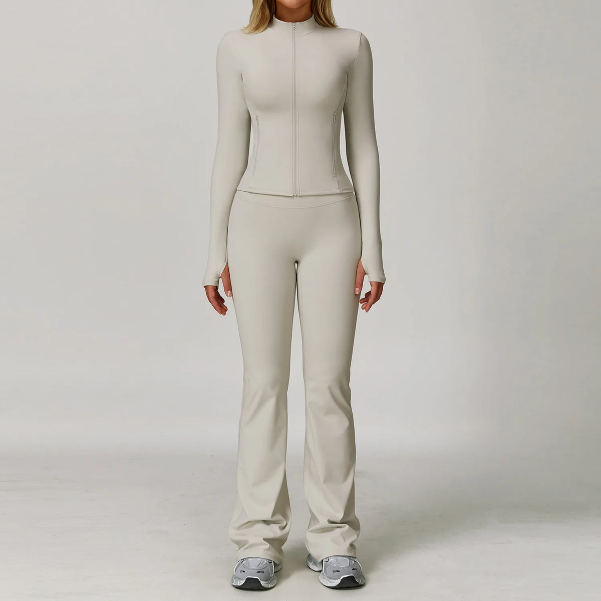A woman wearing a beige long-sleeved top and matching pants from a 3-piece yoga sports set.