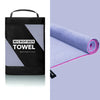 Black microfiber towel with a gray mesh section and pink trim rolled up on a purple background.
