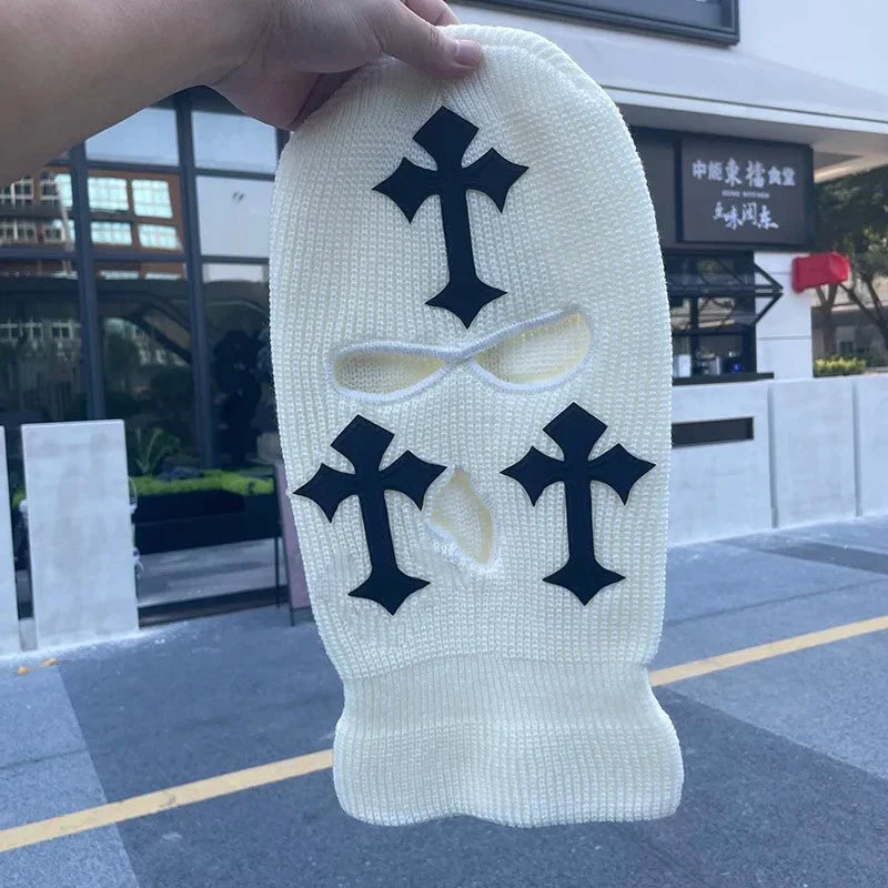 A white tactical knit balaclava beanie hat featuring black cross embroidery on the front.