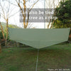 A large, light green tarp is stretched between two points in an outdoor grassy area.