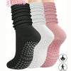 A set of three pairs of black, white, and pink silicone Pilates and yoga socks displayed together.