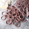 A pile of 50 pieces of mixed color elastic hair bands in a clear plastic bag on a gray surface.
