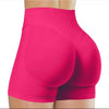Gros plan sur des shorts de yoga sans couture roses vifs taille haute portés par une personne.