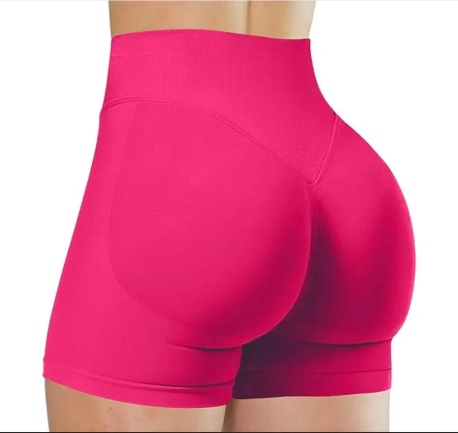 Gros plan sur des shorts de yoga sans couture roses vifs taille haute portés par une personne.