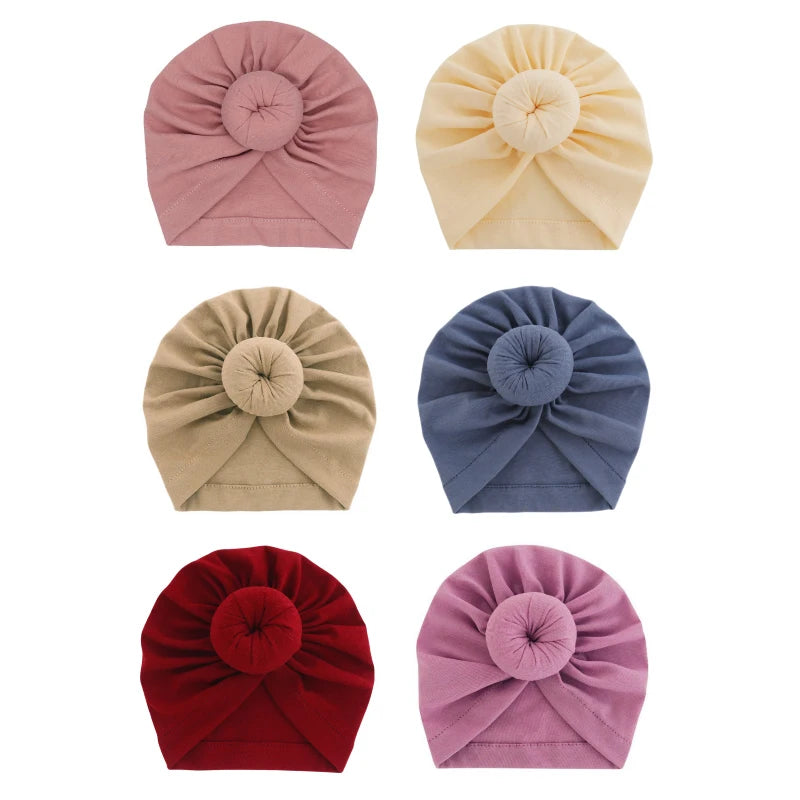 Ein Set aus fünf aus festem Baumwollstoff gemachten Baby-Turban-Headwraps in Rosa, Gelb, Blau und Rot.