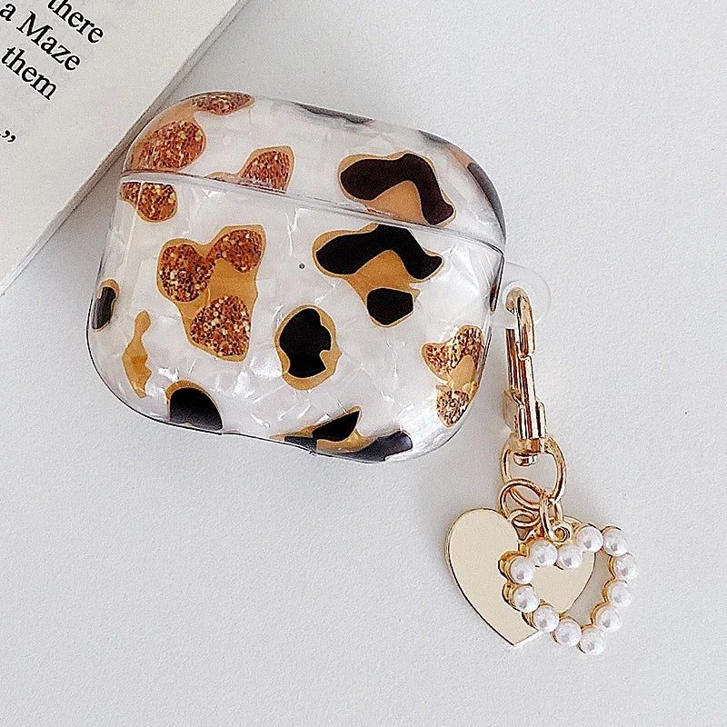 A clear protective case for AirPods Pro featuring a leopard print design with gold and black spots, attached to a gold chain 