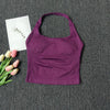 A deep purple seamless yoga and pilates sports bra laid on a dark gray textured surface with a white card and pink tulips.