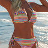 A woman wearing an elegant two-piece swimsuit set with colorful geometric patterns by the ocean.