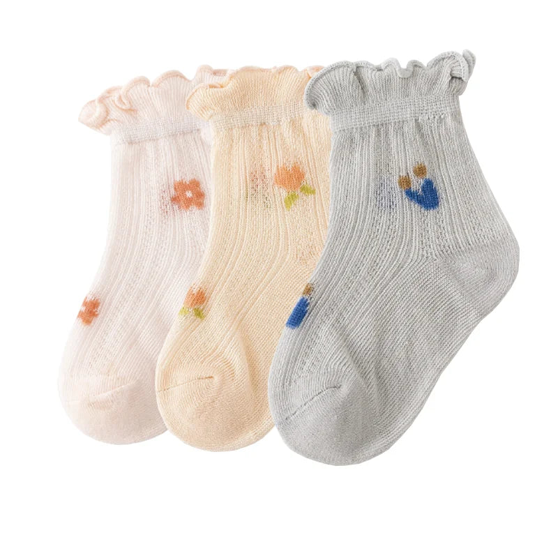 A pack of three thin summer casual baby socks in pink, cream, and light gray.