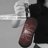 A hand holds a red spider web shaped keychain pouch with a metal keyring.