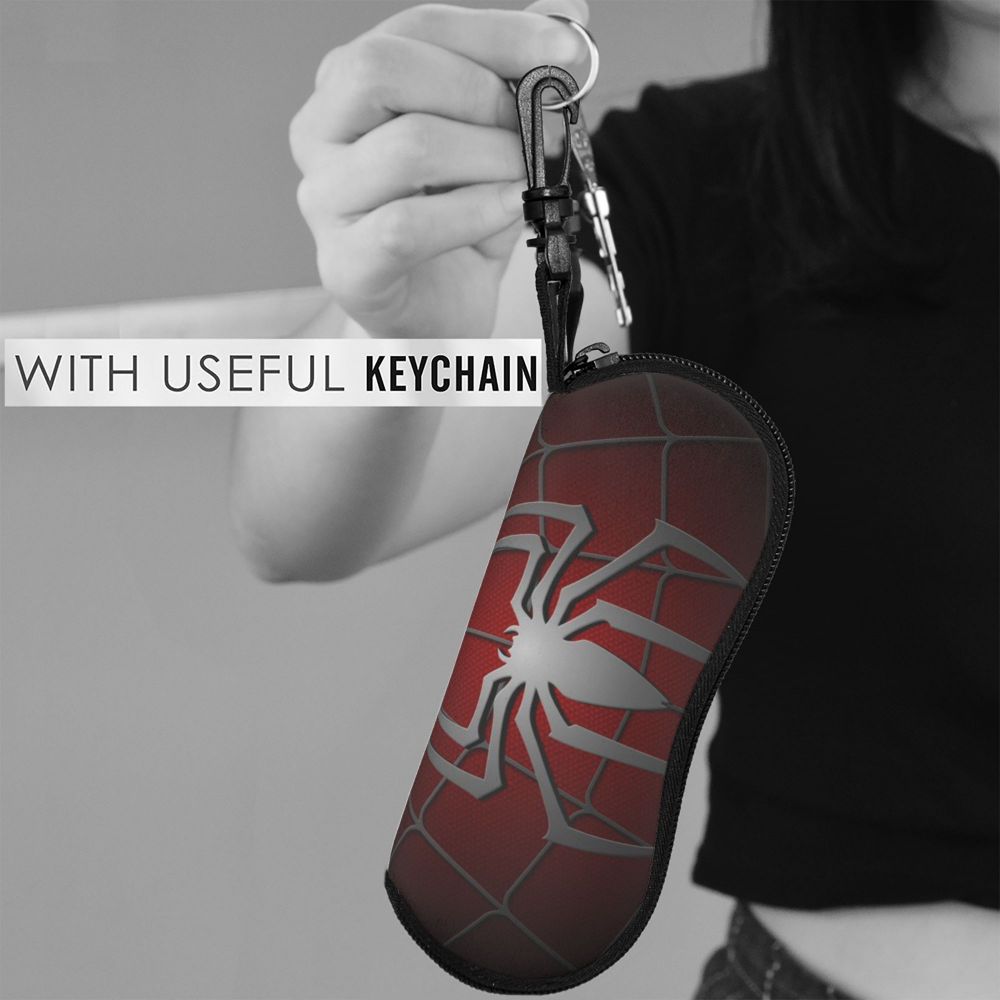 A hand holds a red spider web shaped keychain pouch with a metal keyring.