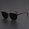 A pair of brown tortoiseshell square sunglasses with dark lenses resting on a dark surface.