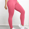 A woman wearing pink high-waisted sports leggings and white sneakers.