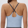 A woman wearing a light blue athletic crisscross tank top with a gray skirt.