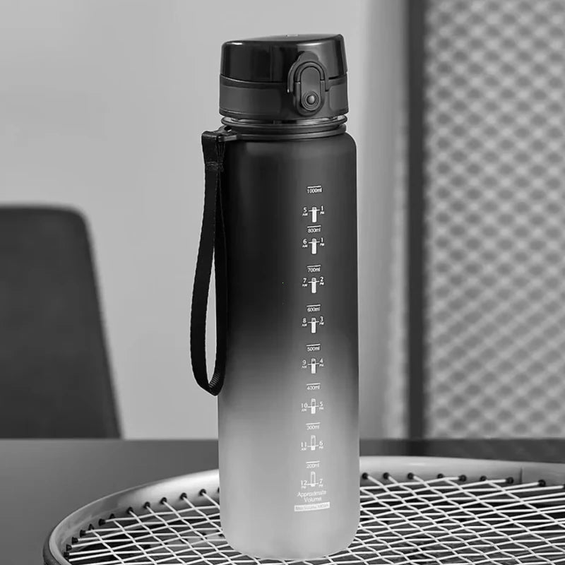 A matte gray sports water bottle with a black cap and strap is displayed on a wire rack.
