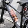 A pink capybara water bottle with a straw and handle is mounted on the frame of a bicycle.