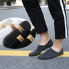 A pair of black breathable boat socks are shown on a person's foot, resting on asphalt.