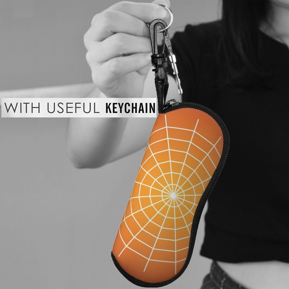 A hand holds an orange spider web shaped eyeglass pouch attached to a keychain against a gray background.
