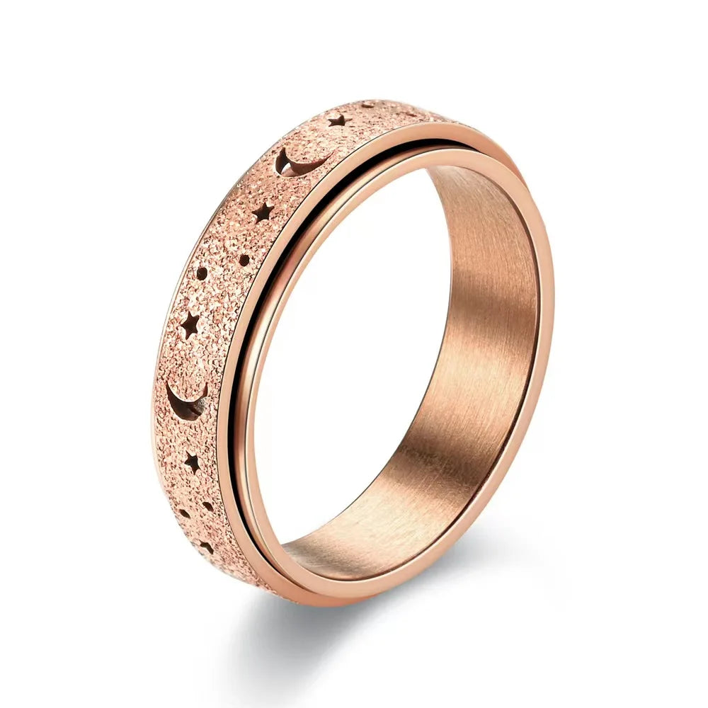A close-up of a rose gold stainless steel ring featuring a textured surface with small moon and star engravings.