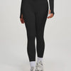 Eine Frau trägt ein schwarzes Yoga-Sportset mit langärmeligem Oberteil und Leggings.
