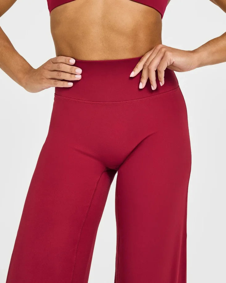 A model wearing high-waist yoga pants in a deep red color.