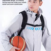 A young man wearing a light gray jacket with a buckle structure on the chest carrying an orange basketball.