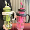 A clear reusable water bottle with a straw and handle, featuring ice cream themed colors like lime green and pink.
