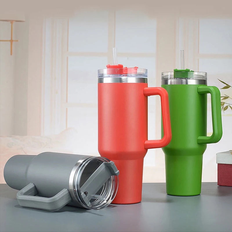 Un set de trois grandes tasses isothermes en acier inoxydable rouge, vert et gris avec paille.
