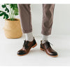 Une paire de bottes en cuir marron avec des chaussettes grises et un pantalon vert olive.