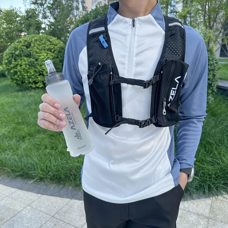 A person wearing a black hydration vest holds a clear silicone water bottle outdoors.