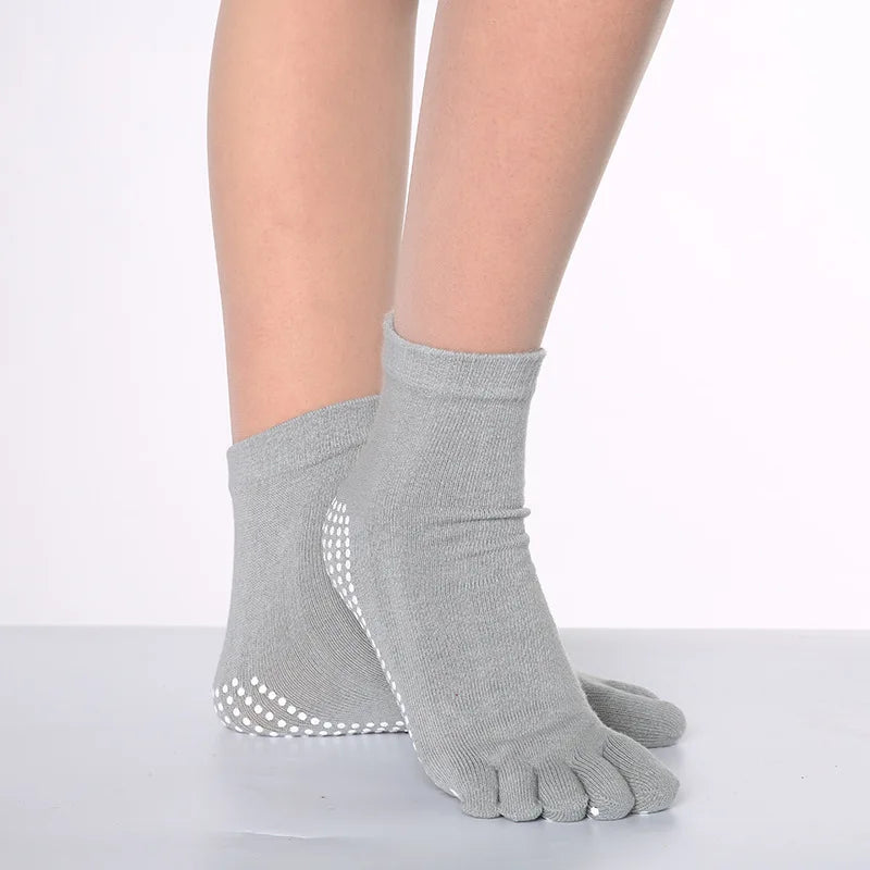Gray yoga socks worn on a foot, showing the texture and dotted pattern.