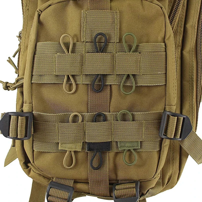 A close-up view of a tan tactical antenna binding buckle strap system on a green backpack.
