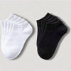 Un juego de calcetines unisex de algodón transpirable blanco y negro, colocados sobre una superficie clara.
