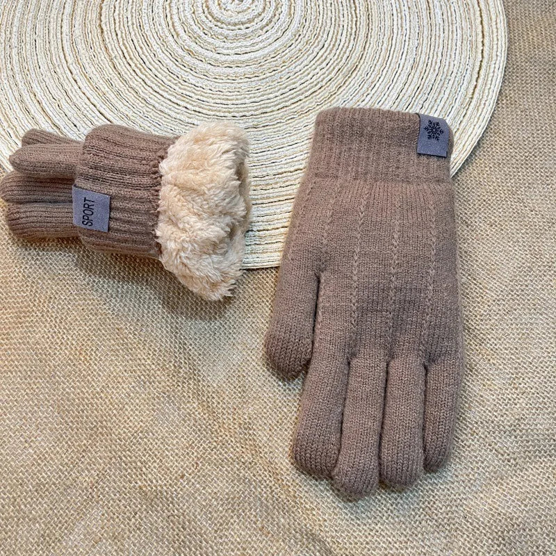 A pair of brown knit gloves with a fluffy cuff resting on a beige woven surface.