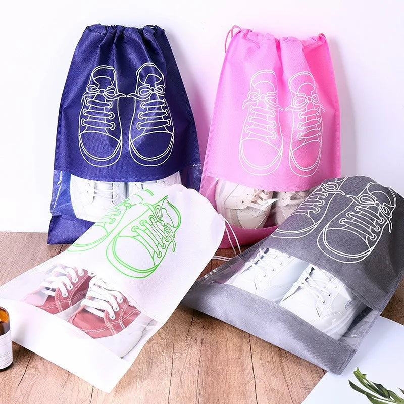 A collection of reusable non-woven shoe storage bags in blue, pink, and gray are displayed on a wooden surface.