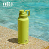 Tasse isotherme en acier inoxydable vert lime posée sur une roche à côté de de l'eau claire.