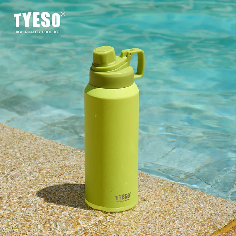 Tasse isotherme en acier inoxydable vert lime posée sur une roche à côté de de l'eau claire.