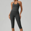 Eine Frau trägt ein dunkelgraues Yoga-Activewear-Set bestehend aus einem Tanktop und Leggings.