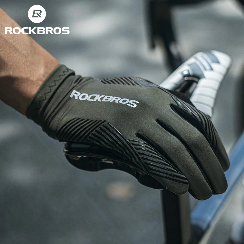 A hand wearing black Rockbros cycling performance gloves gripping a bicycle handlebar.