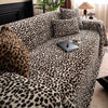 A plush sofa covered in a leopard print fabric with various pillows and decorative items.