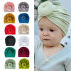 Baby trägt einen hellgrünen Baumwollturban, umgeben von verschiedenen Stoffoptionen in einfarbigen Farben.