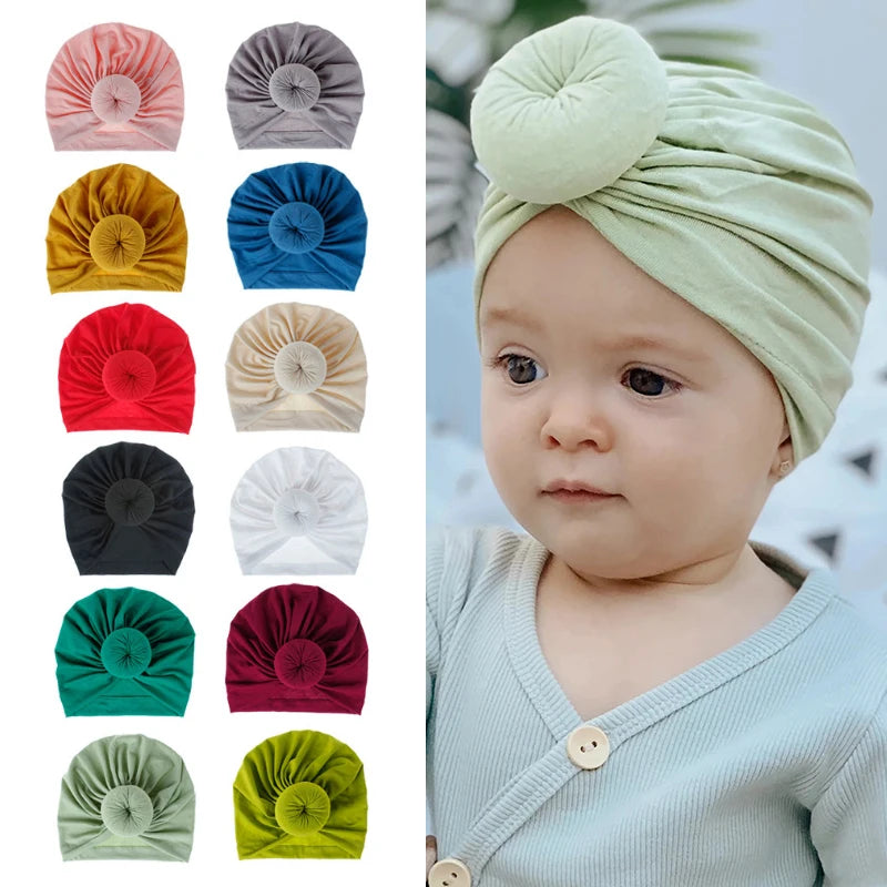 Baby trägt einen hellgrünen Baumwollturban, umgeben von verschiedenen Stoffoptionen in einfarbigen Farben.