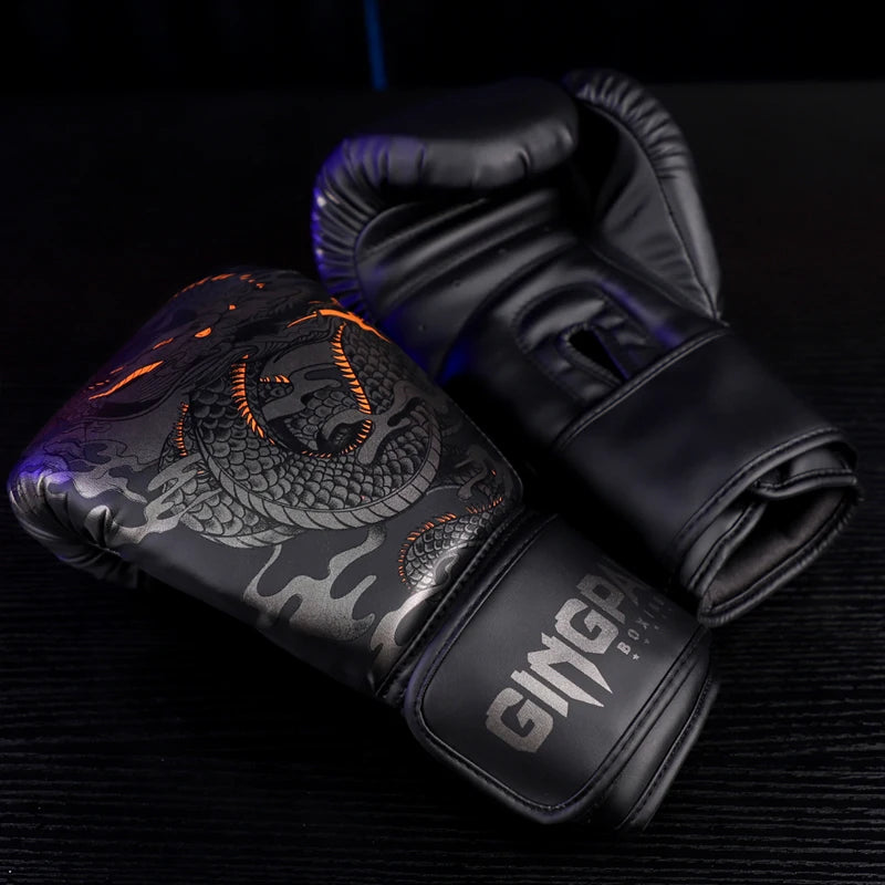 Ein Paar schwarzer Boxhandschuhe mit grau-orangefarbener Drachen-Design, im Nahaufnahme auf dunker Oberfläche.