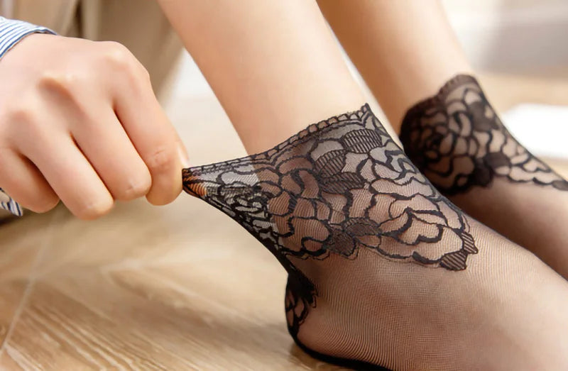 Close-up of a person wearing black lace mesh ankle socks on their foot.