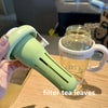 A hand holds a light green reusable leak-proof water bottle with a straw and handle next to a jar of ice cream.