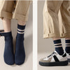 A pair of navy blue ribbed socks with light stripes worn on a person's feet.
