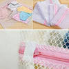 Primer plano de bolsas organizadoras de ropa de malla rosa y blanca llenas de ropa de varios colores.