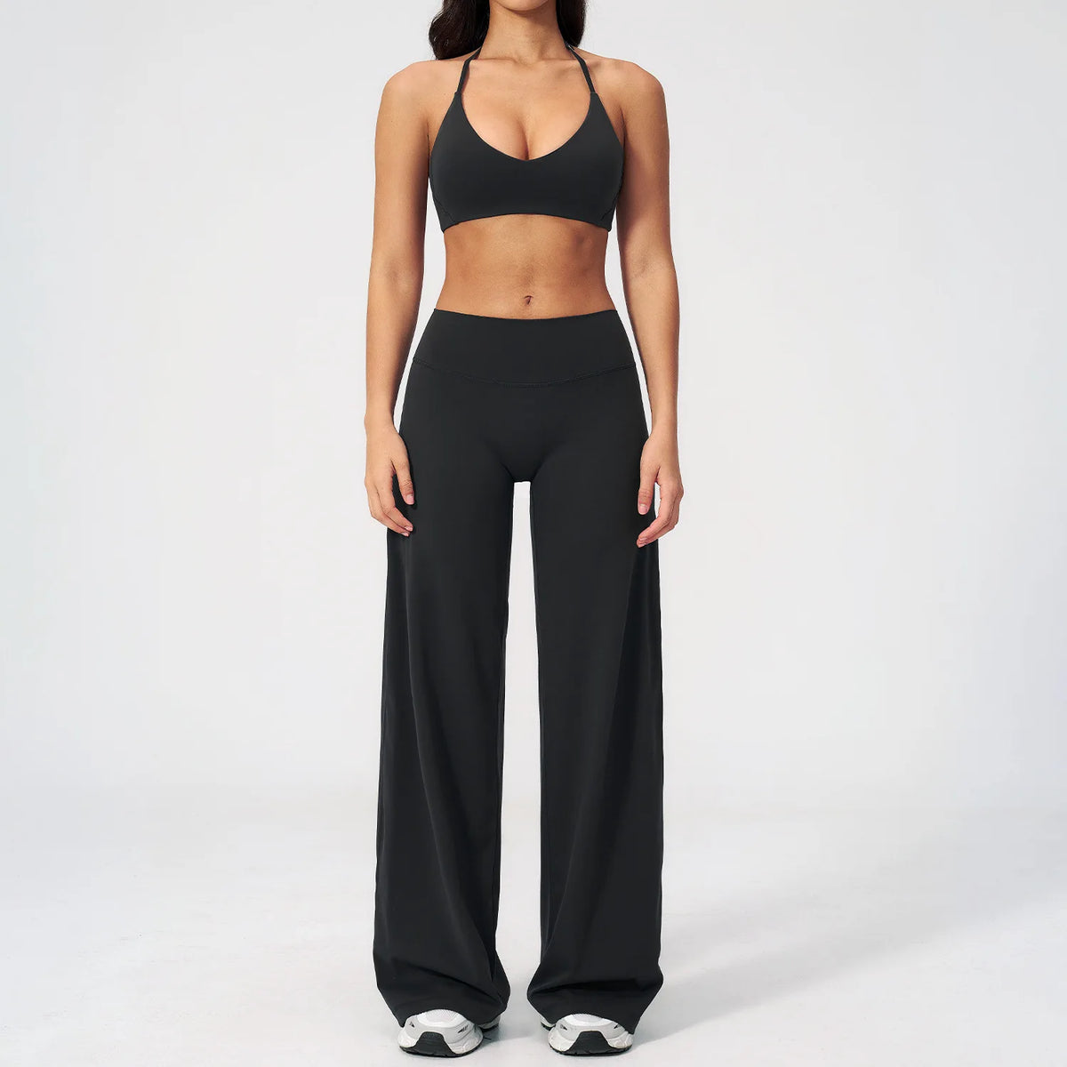 A woman wearing a black women's premium fitness tracksuit top and matching pants.