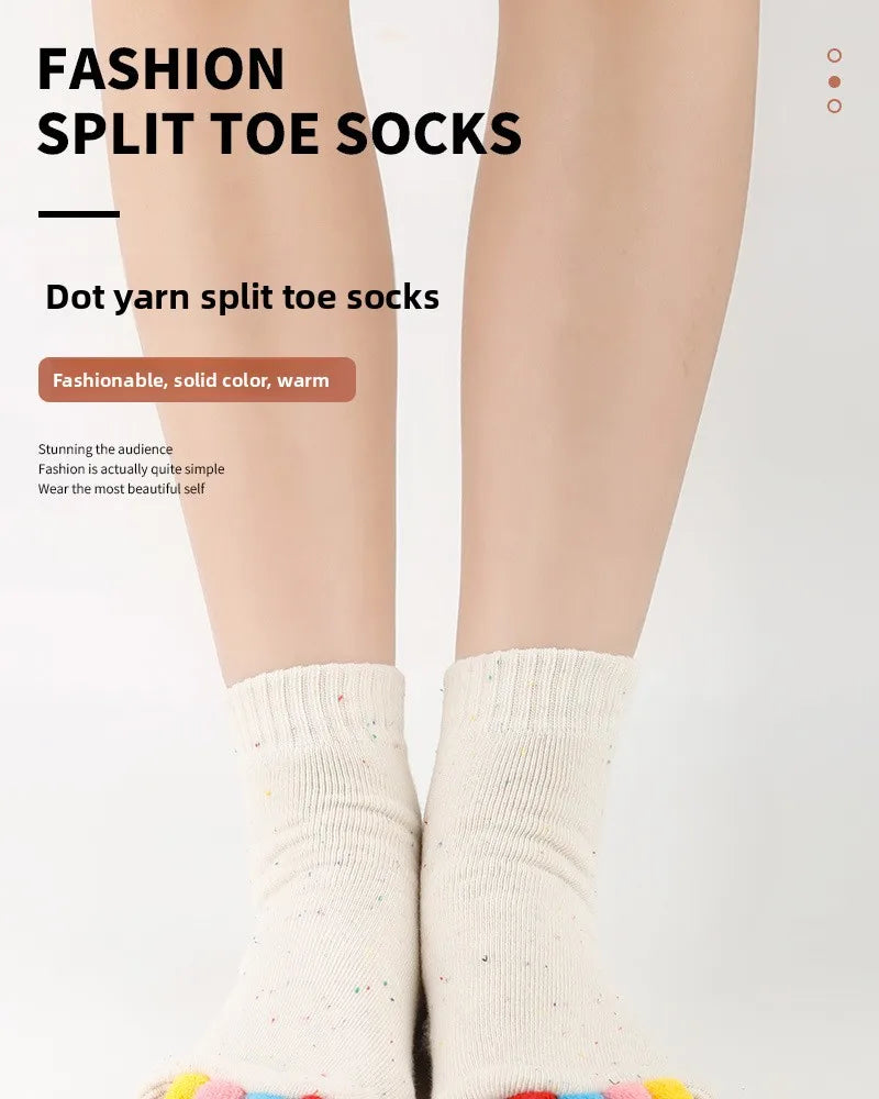 Close-up of a model wearing white split toe socks with colorful accents.