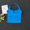 Haut sans bretelles bleu vif, unis, pour le yoga et la fitness, posé sur fond gris foncé à côté de tulipes roses.